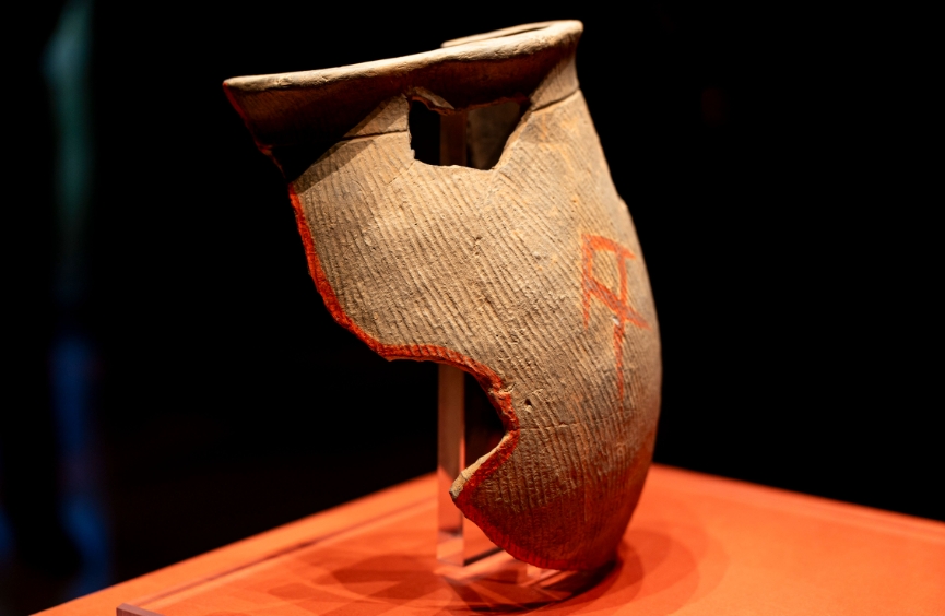 朱書扁壺（展廳中為復(fù)制品，真品現(xiàn)藏于中國考古博物館）。扁壺為泥質(zhì)灰陶，器表飾細(xì)條豎藍(lán)紋，是陶寺先民打水的工具。這件破碎的扁壺有朱書文字位于兩面，十分珍貴。